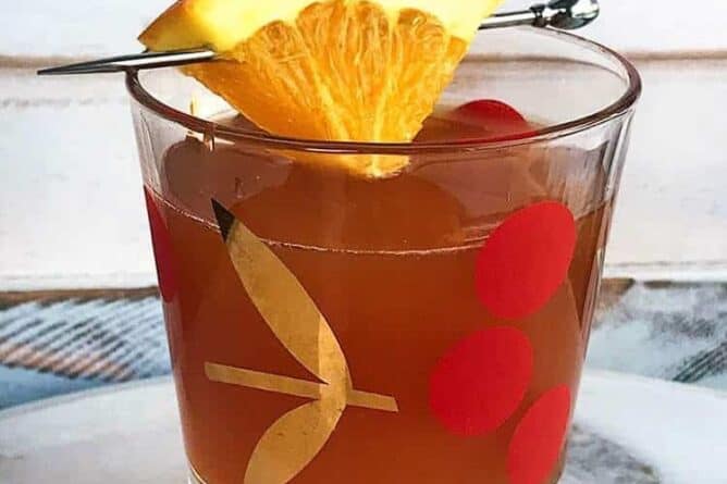 Alabama Slammer Cocktail in Cherries vintage glass garnish with a small slice of orange