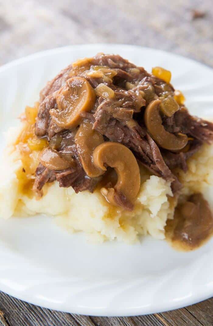 beef and mushroom instant pot pot roast over mashed potatoes in a white plate