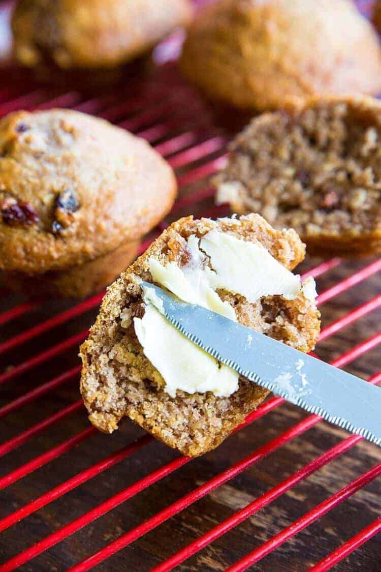 Adding Spread to Half Sliced Oat Bran Muffins on Red Cooling Rack