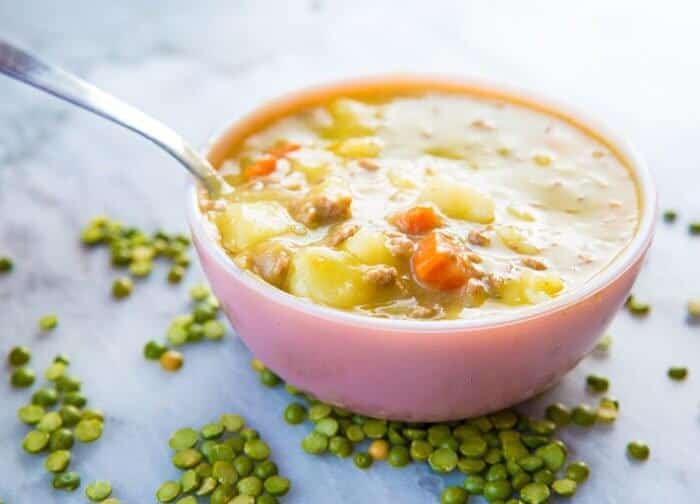 Creamy Split Pea Hamburger Soup in pink Pyrex bowl with spoon in it