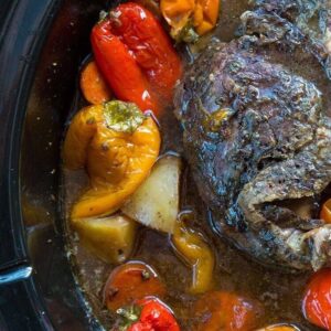 close up roast in the bottom of slow cooker with water and surrounded with all the vegetables