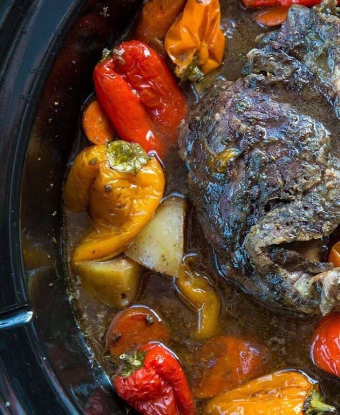 close up roast in the bottom of slow cooker with water and surrounded with all the vegetables