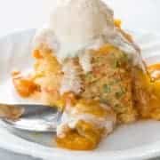 Close up of Confetti Cake in a White Plate Topped with Peach Topping and Vanilla Ice Cream
