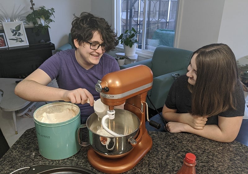 slowly adding a scoop of flour into the mixer