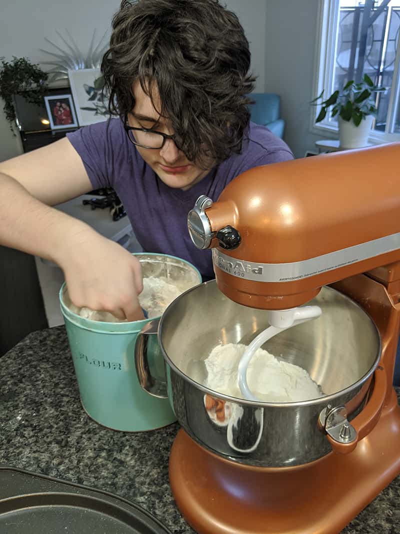 getting another scoop of flour to be added slowly into the mixer