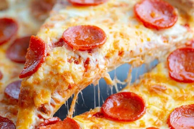 close up slice of simple pizza crust stuffed with cheese and pepperoni