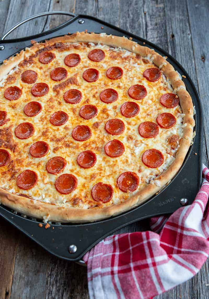 close up simple pizza crust stuffed with cheese and pepperoni in a large pizza pan