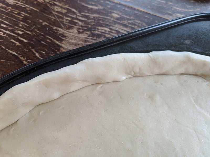 simple pizza dough in a pizza pan