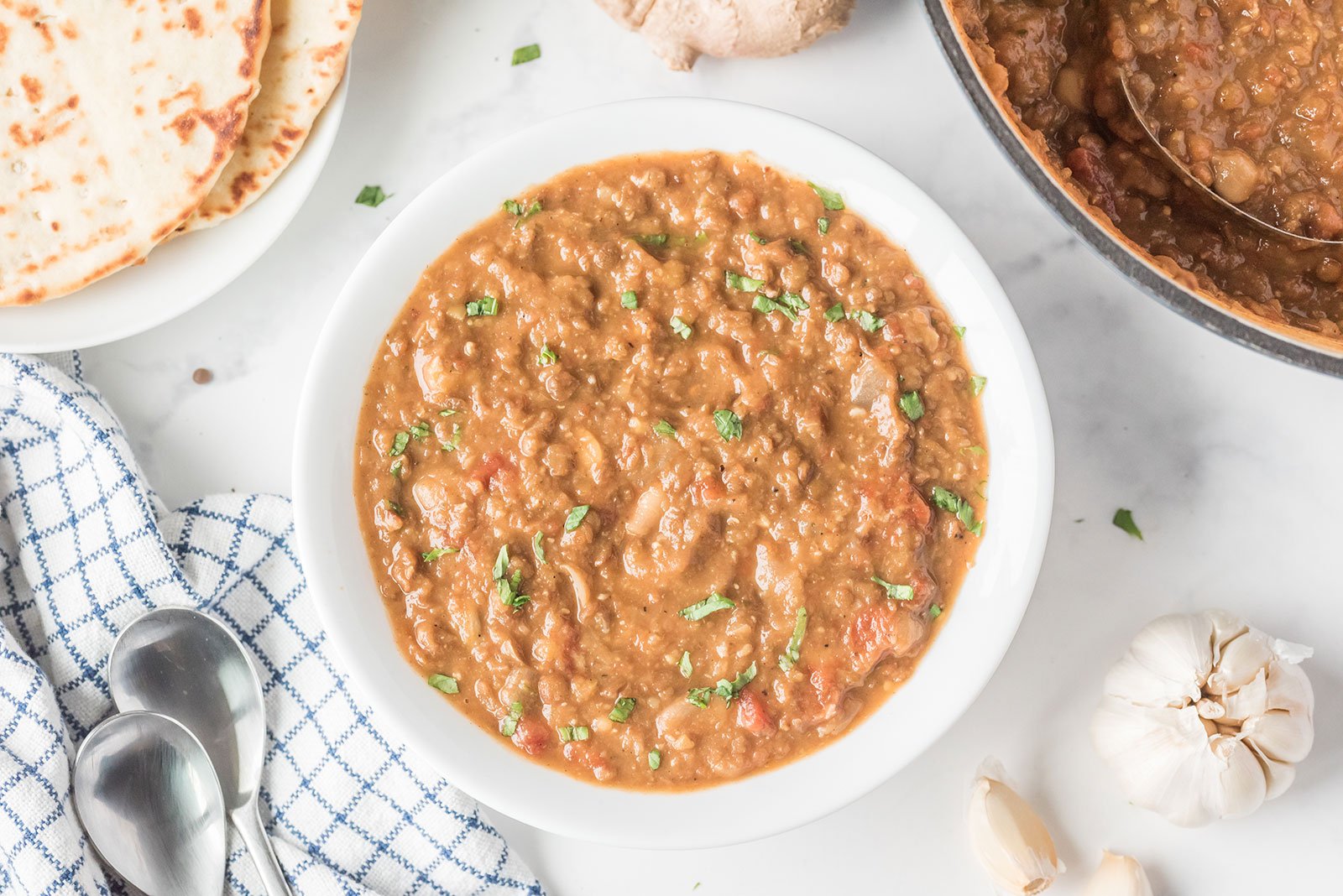Hearty red lentil and bean soup garnished with herbs.