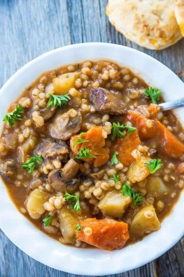 close up Beef & Barley Stew in a white bowl with spoon