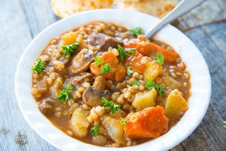 Beef & Barley Stew in a white bowl with spoon