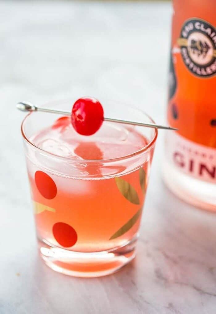 Gin Rickey Cocktail in Collins glass with ice cubes garnish with cherry on pick