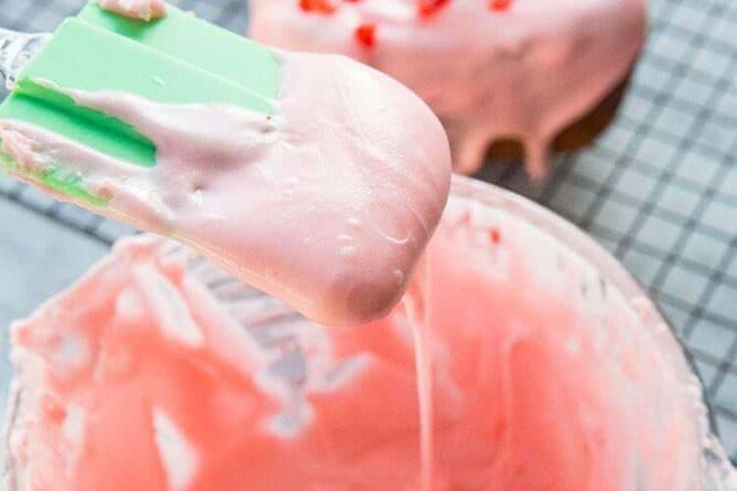 Close up Cherry Icing Glaze in a Pyrex measuring cup with green spatula