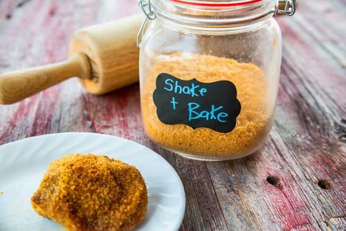 Fried chicken coated with Homemade Shake and Bake in a white plate. Shake and Bake in a Glass Jar with Lid.