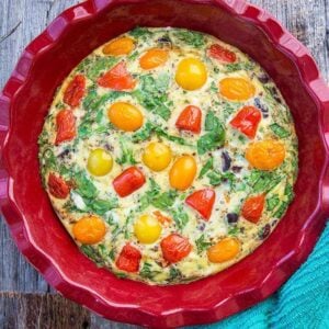 Mediterranean Vegetable Frittata in Large Red Bowl with cherry tomatoes, chopped kalamata olives and crumpled feta