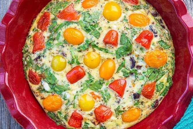 Mediterranean Vegetable Frittata in Large Red Bowl with cherry tomatoes, chopped kalamata olives and crumpled feta