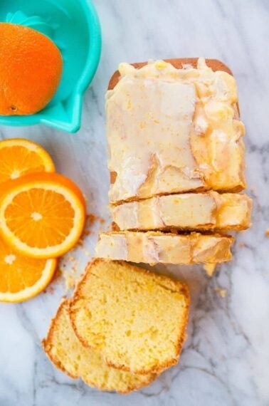 Top down shot of Sliced Orange Loaf Cake Topped with Orange Icing Glaze, Sliced Orange on the side