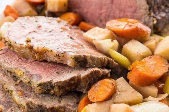 Close up of Sliced Slow Cooker Red Wine Striploin Roast Beef Served with Vegetables and Gravy