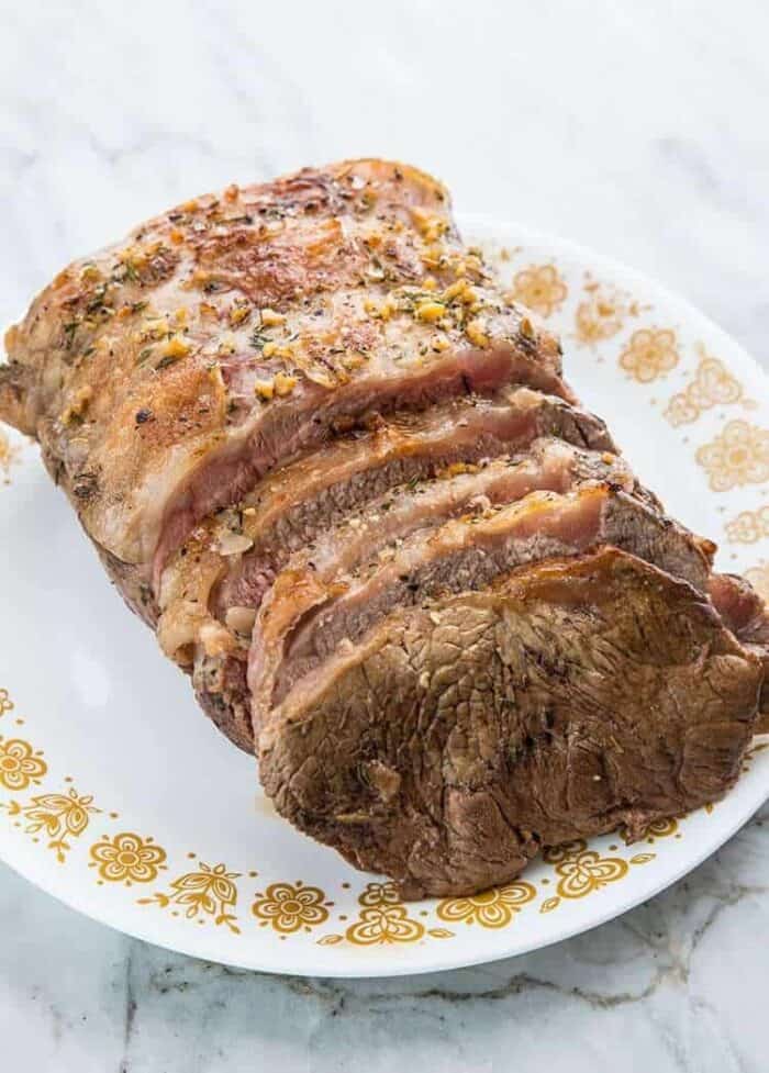 Outer Crust of Striploin Roast Beef with butter herb paste on a white plate with gold floral prints