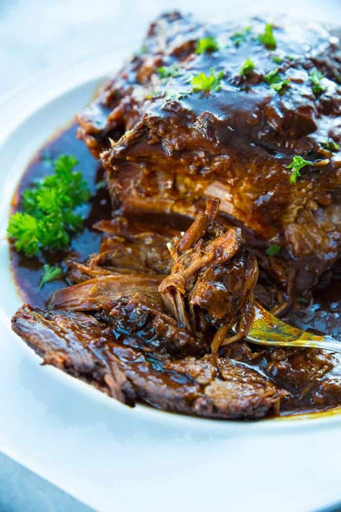 Slow Cooker Brisket in a white plate with root beer and BBQ sauce