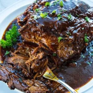 Slow Cooker Brisket in a white plate with root beer and BBQ sauce