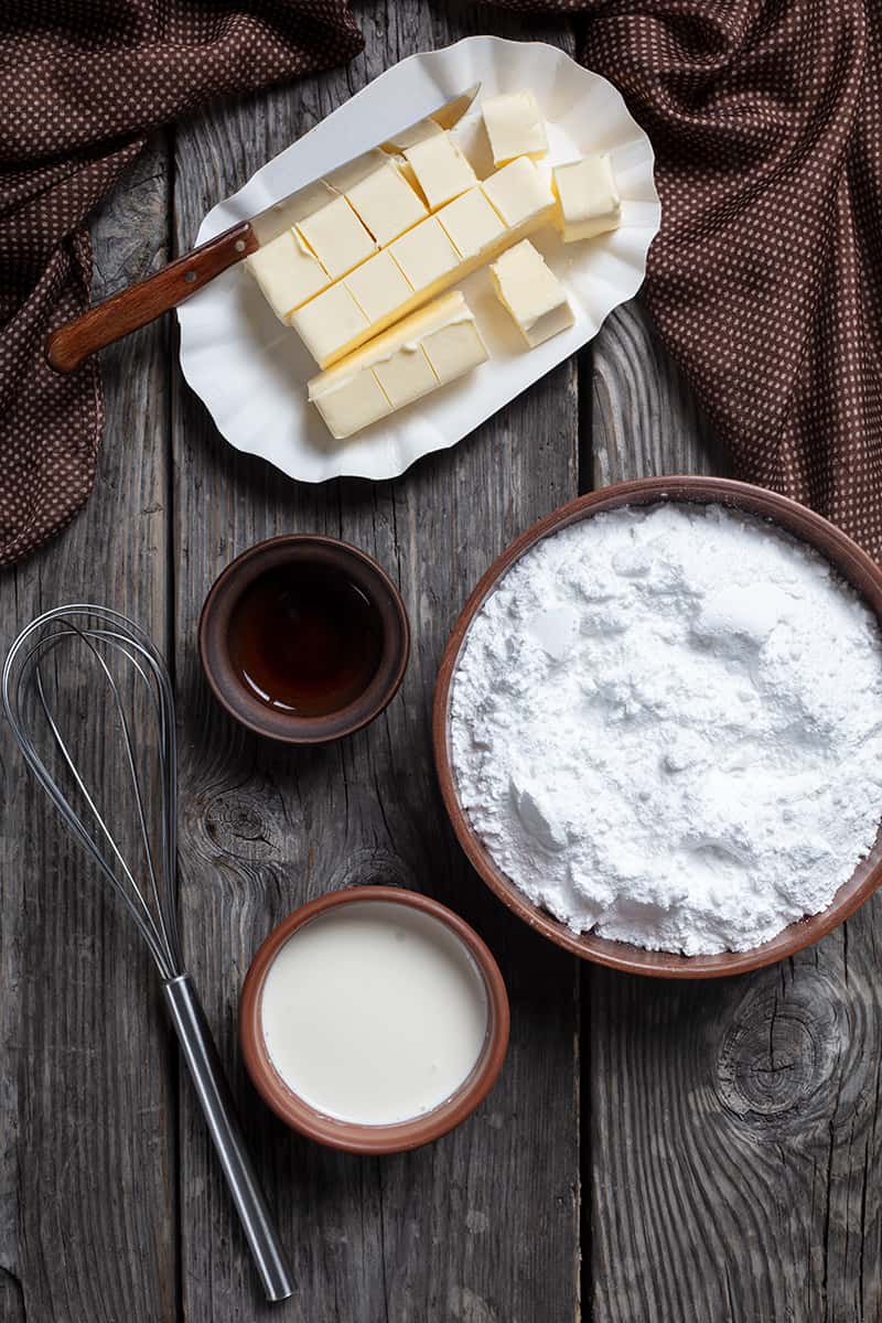 buttercream frosting ingredients on a wood background with brown polka dots tablecloth on side