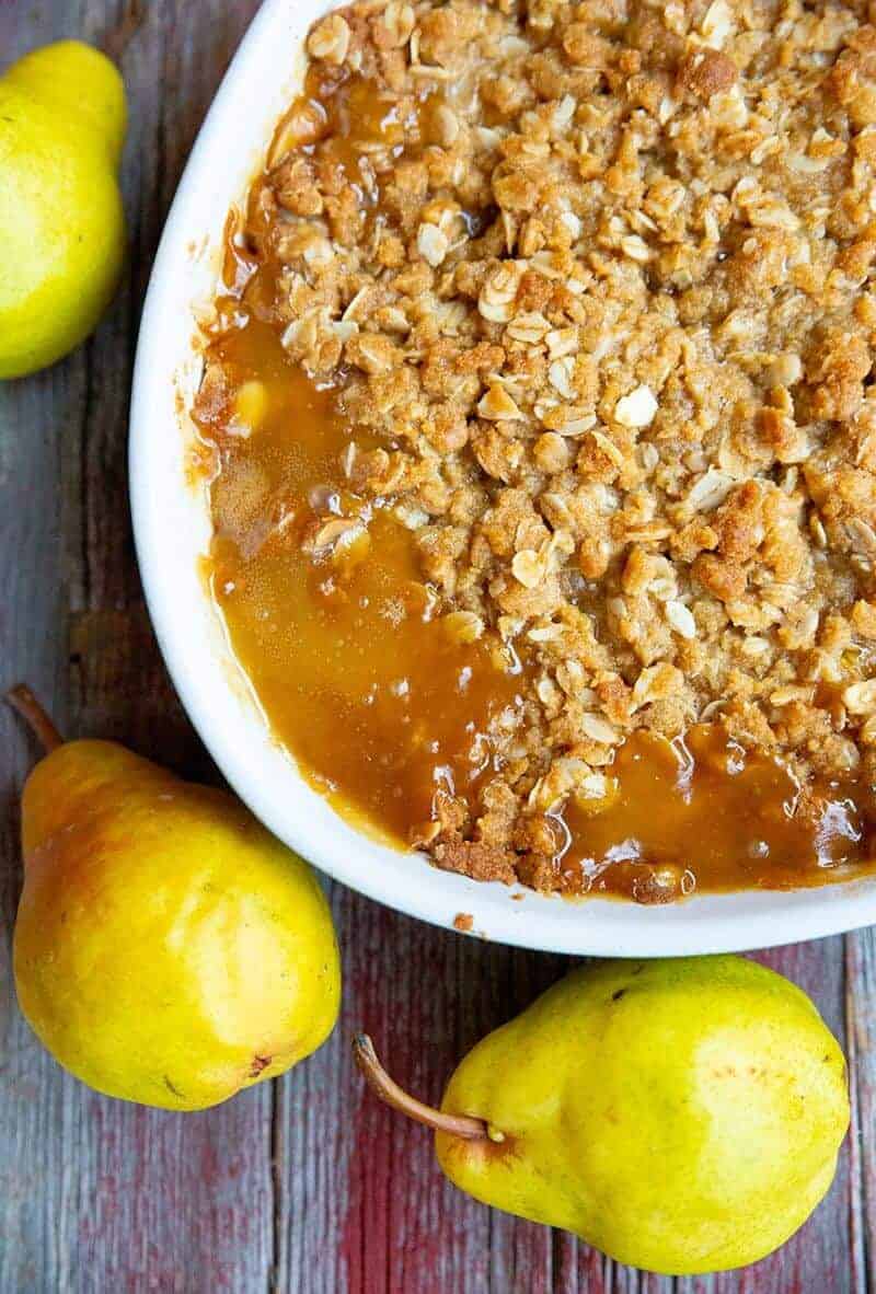close up oval white plate with Pear Crisp, 3 pieces Yellow Bartlett Pears on background