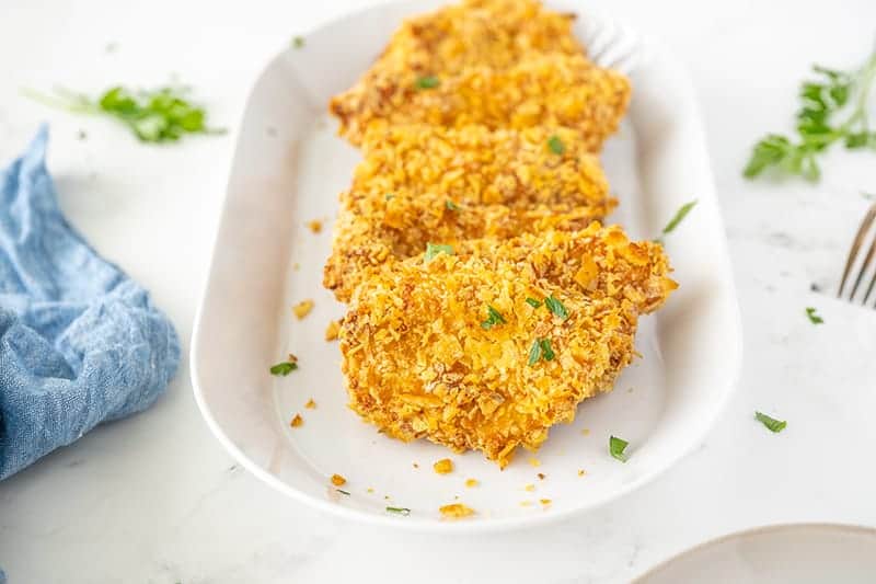 three pieces fried potato chip chicken on a white platter