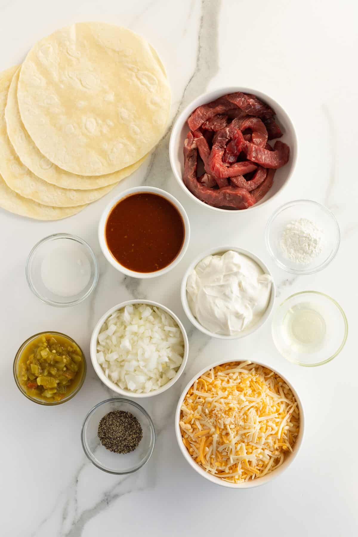 sour cream steak enchiladas ingredients in small white bowls
