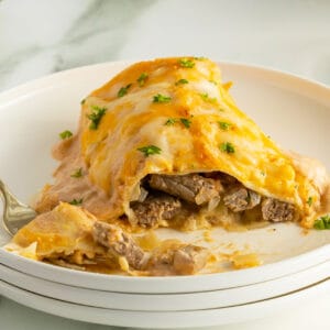 sour cream steak enchilada on a stack of white plates