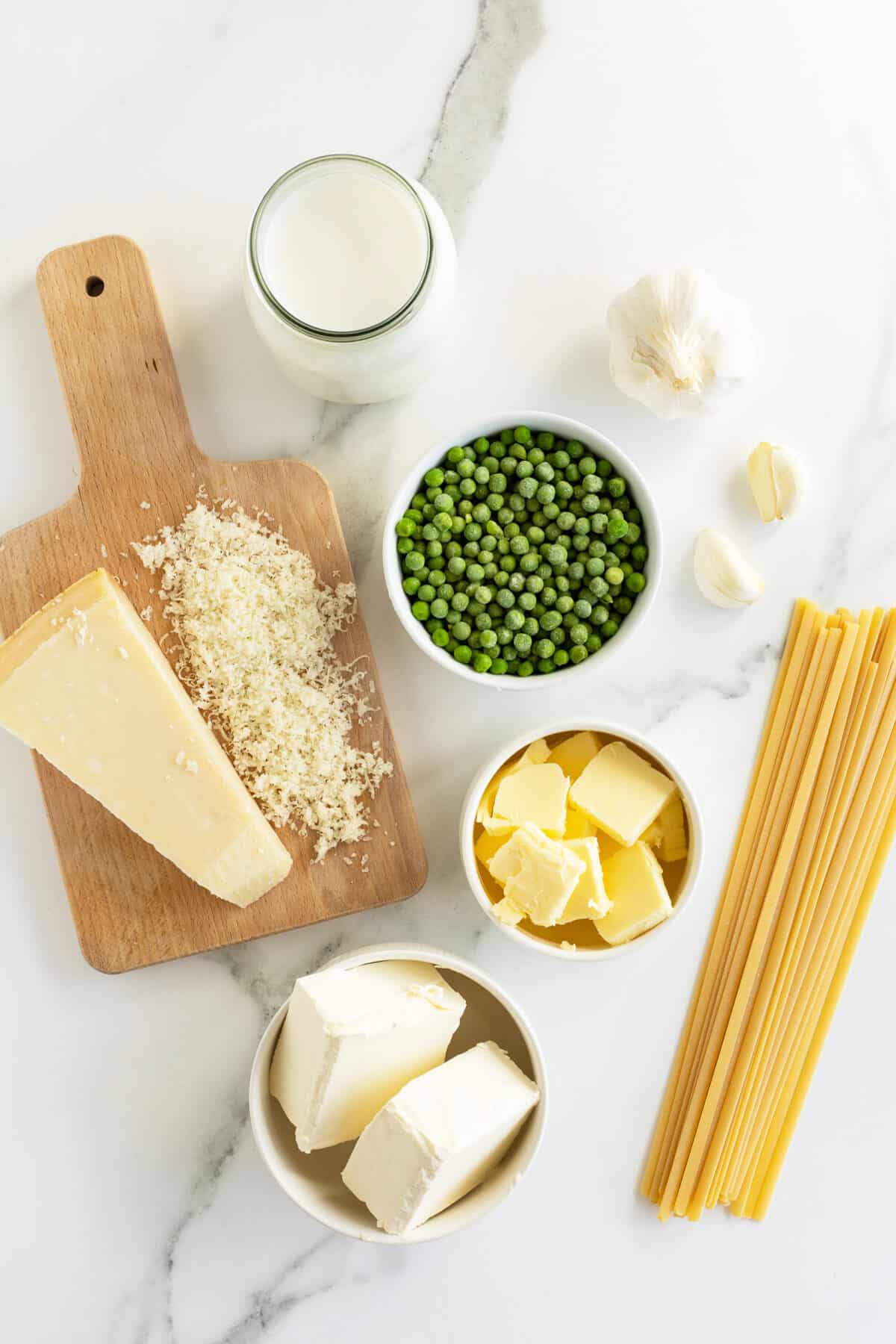 5 ingredient cream cheese Alfredo sauce ingredients in white bowls and cheese on a cutting board