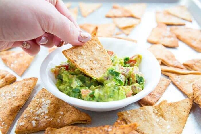 Dipping the Homemade Pita Chips into dipping dish with tomatoes, garlic, cilantro, onions and avocado 