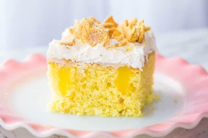 A Slice of Lemon Better Than Sex Cake Topped with Whipped Cream and Crushed Lemon Cookies in Ruffle Plate