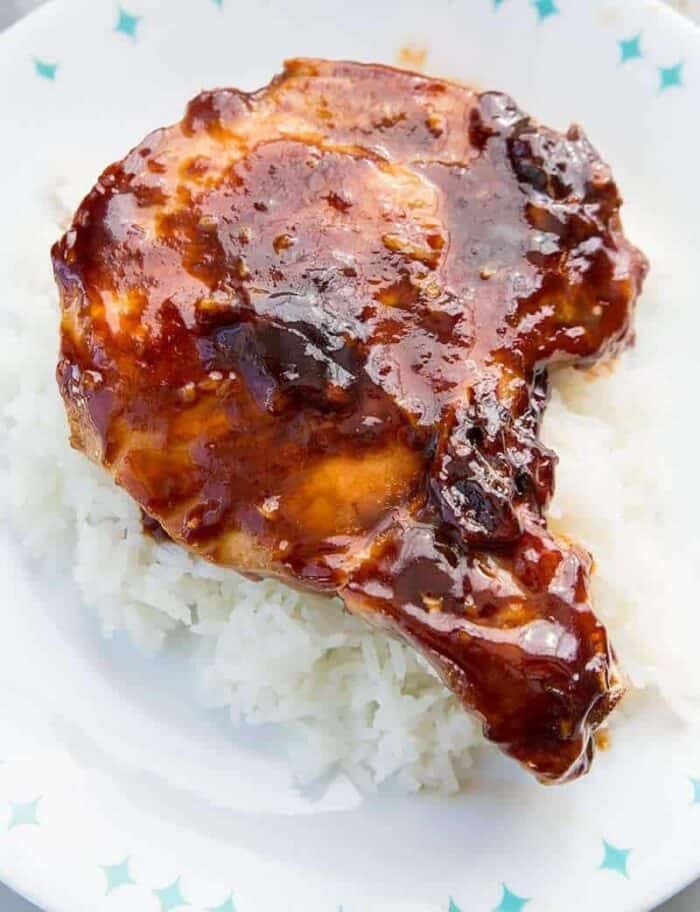 Close up of a sauce covered pork chop on white rice