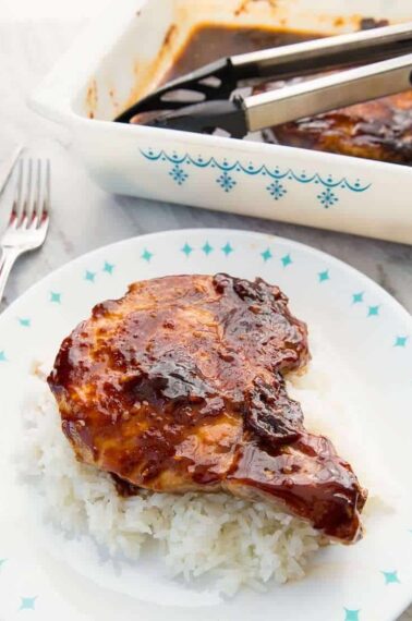 close up of Saucy Baked Pork Chops on a bed of rice on a blue and white plate