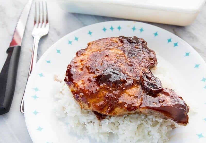 Saucy Baked Pork Chops on a bed of rice on a blue and white plate