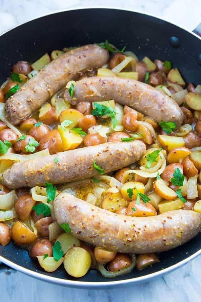 Close up of Sweet Mustard Sausage and Potato Skillet with parsley in a large black skillet
