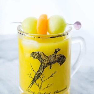 Close up of Vodka Melon Ball Cocktail in a Ring Necked Pheasant Glass Mug garnish with melon balls on pick