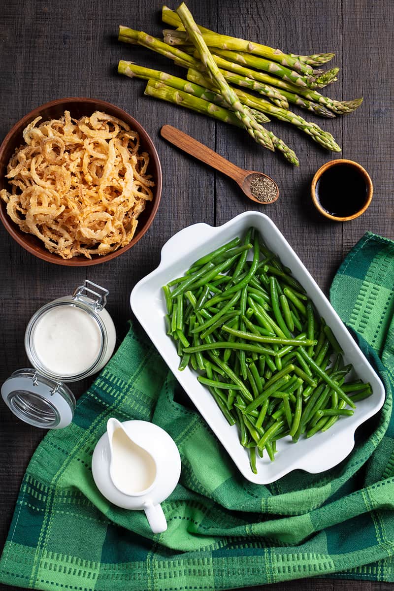 Asparagus Green Bean Casserole ingredients in wood background with green tablecloth