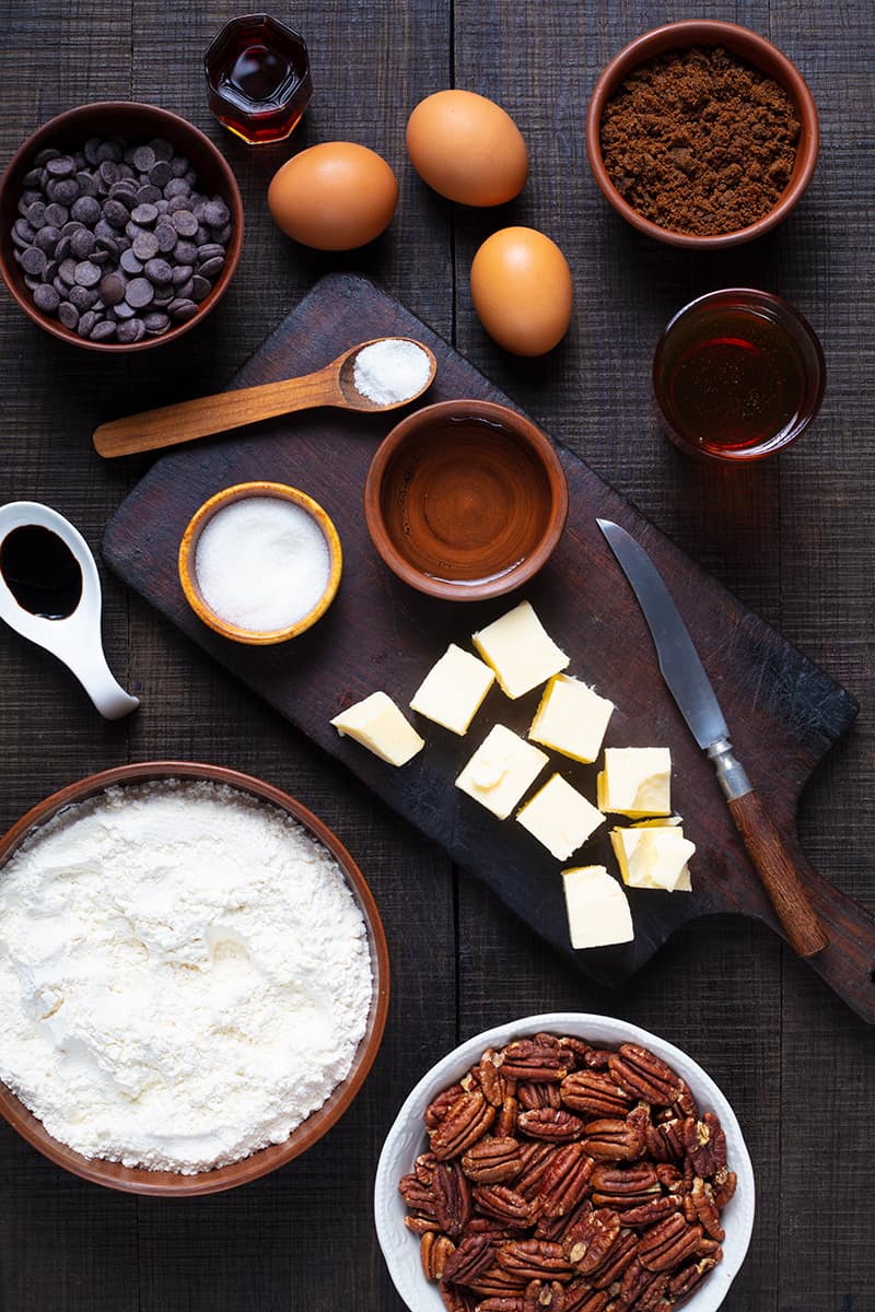 Chocolate Pecan Pie ingredients on a wooden cutting board and a dark wood background