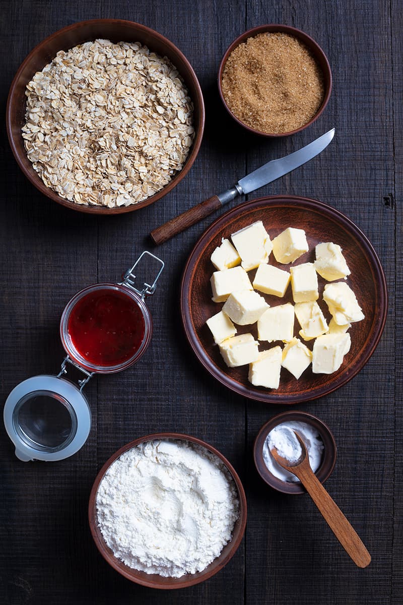 ingredients for cranberry oatmeal bar cookies in a dark wood background