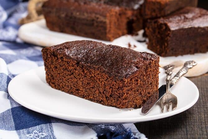 slices of Old Fashioned Gingerbread on white plates with fork and bread knife
