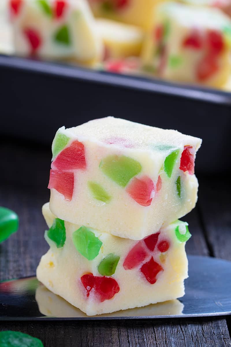 close up slice of Christmas Fudge in a cake spatula, Christmas Fudge pan on its background