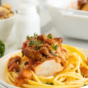 Chicken Parmesan Casserole on a white plate with pasta parsley on top