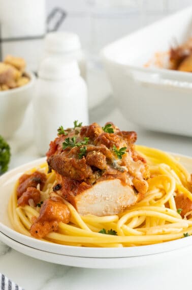 Chicken Parmesan Casserole on a white plate with pasta parsley on top