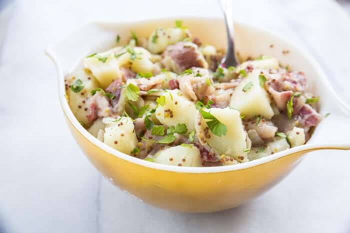 German Potato Salad in a Yellow Pyrex Bowl with Chopped Parsley on Top