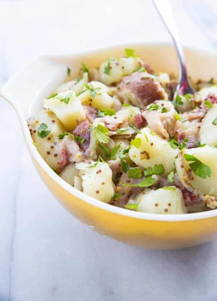 Close up of Classic German Potato Salad in a Pyrex bowl on a Marble Background