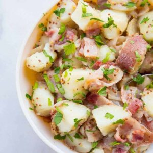 Top down shot of Classic German Potato Salad in a Pyrex bowl on a Marble Background