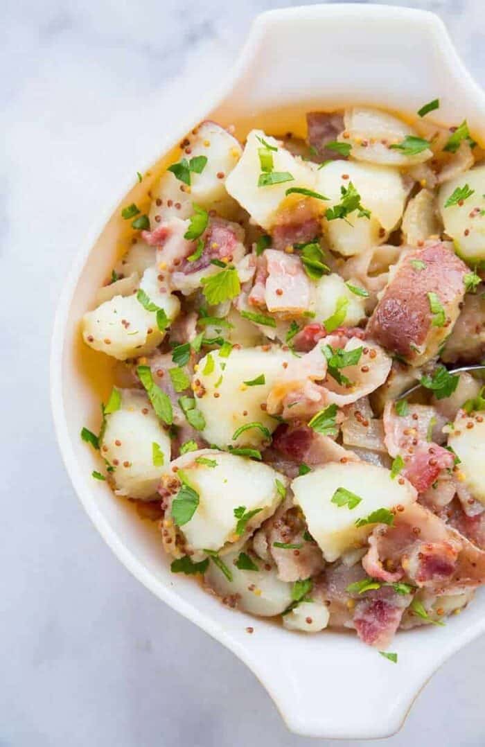 Top down shot of Classic German Potato Salad in a Pyrex bowl on a Marble Background