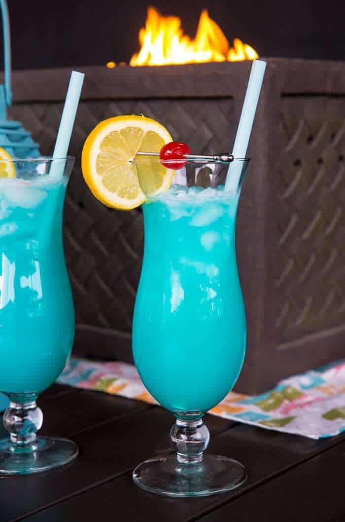 Two Blue Lagoon Cocktails in Front of a Tabletop Firepit